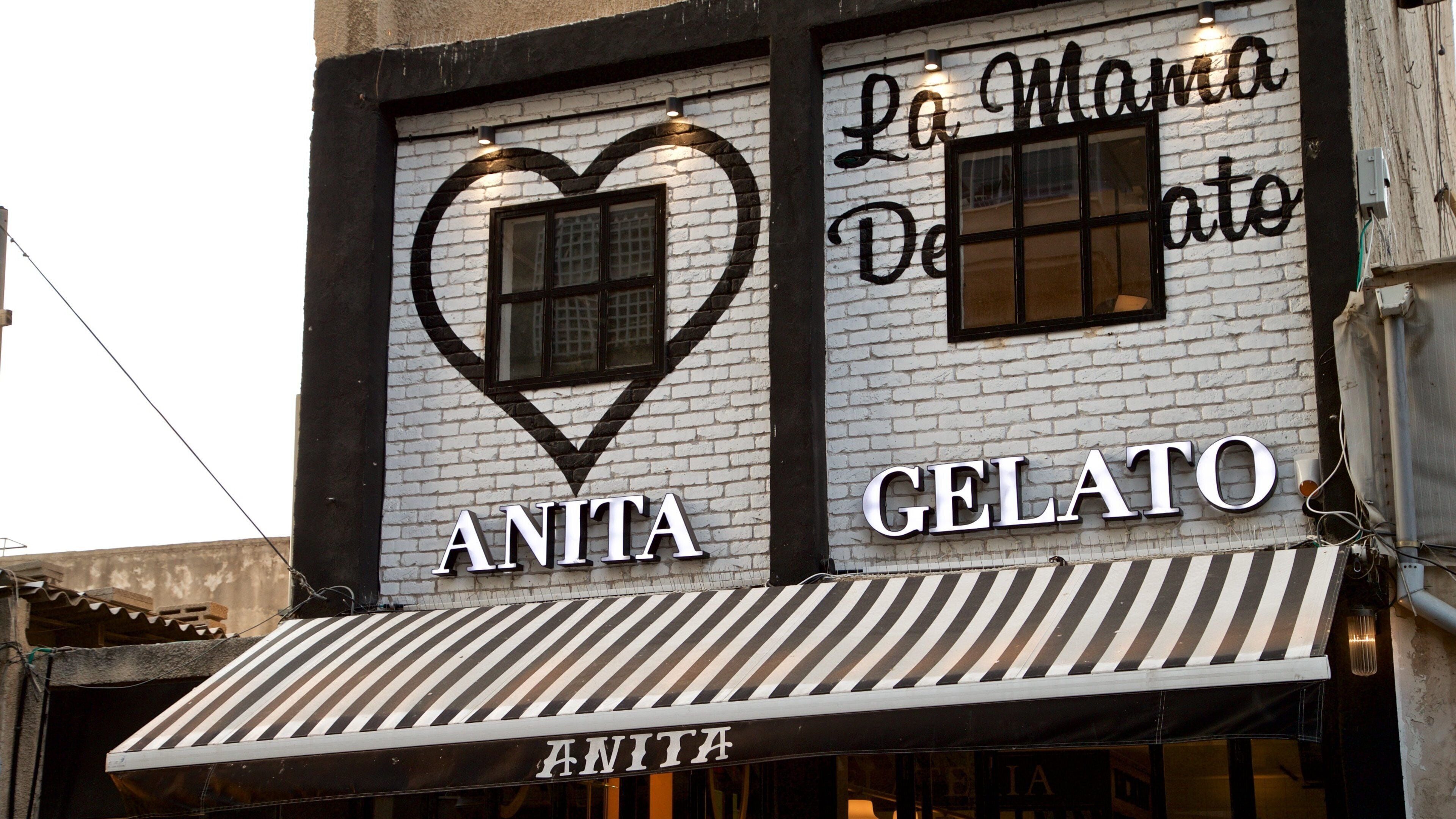 A storefront with a heart-shaped sign and the words "ANITA GELATO" on a white brick wall.