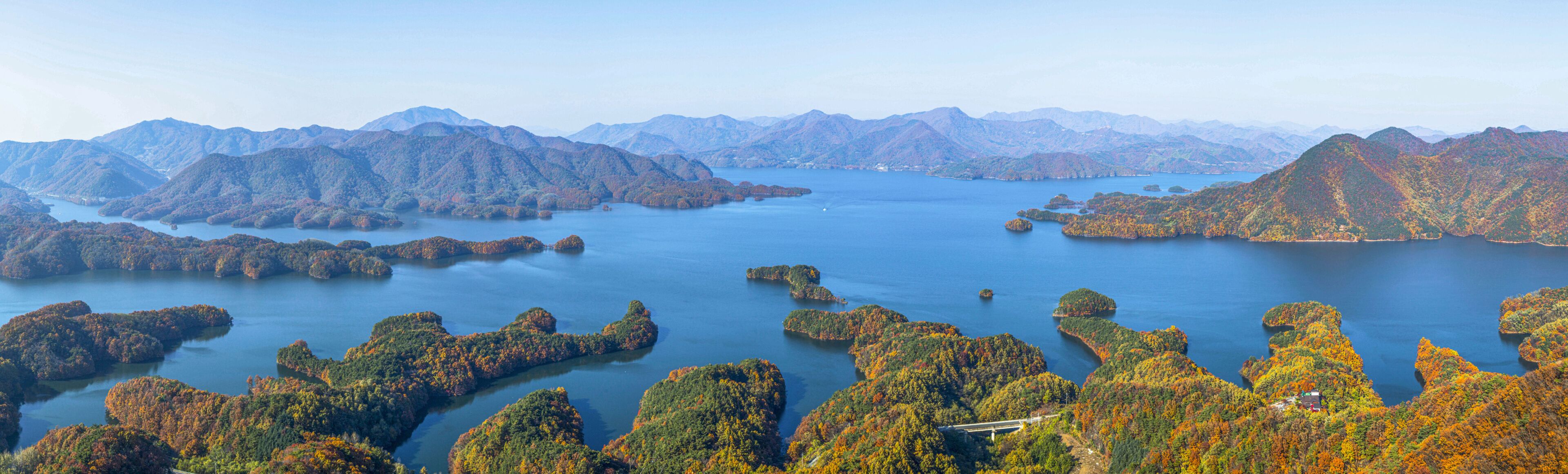 A mountainous landscape with a large body of water surrounded by forested islands.