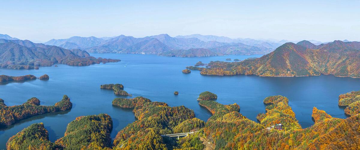 A mountainous landscape with a large body of water surrounded by forested islands.