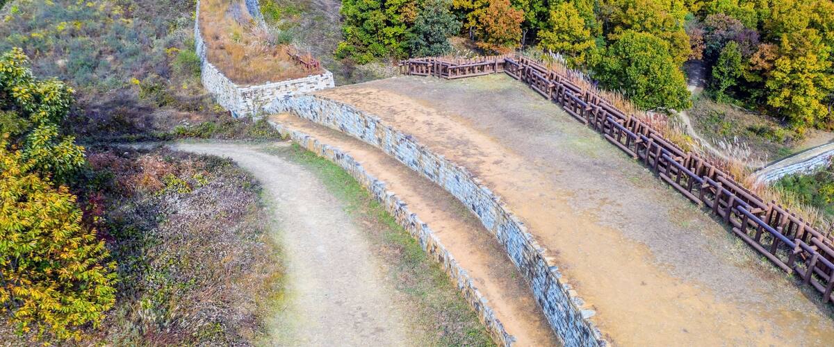 A winding dirt path with stone walls and wooden fences.