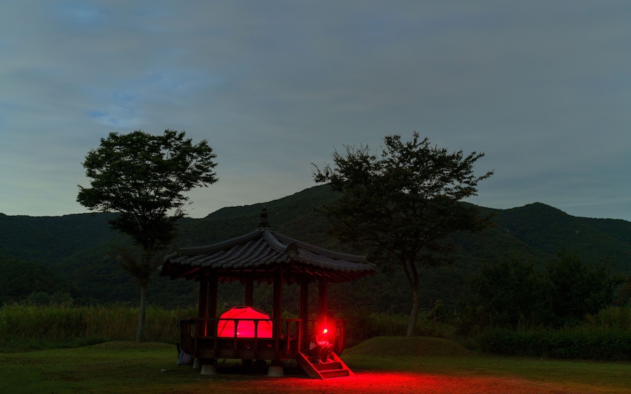 Red light glows from a tent in a gazebo