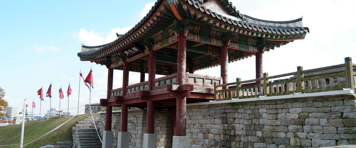 A traditional Korean pavilion with a tiled roof, red pillars, and stone steps leading up to it.