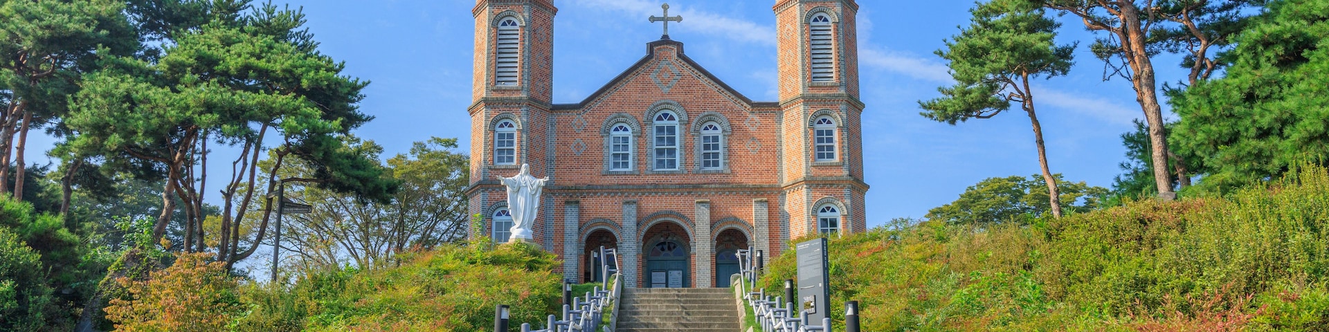 Una iglesia con dos torres, una estatua y una escalera que la conduce.