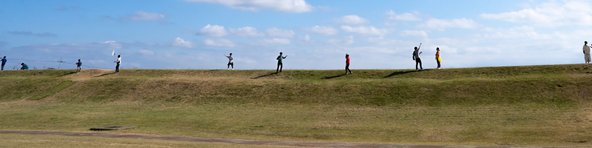 언덕에 올라 파란 가을 하늘을 향하여 연 날리기를 즐기는 사람들