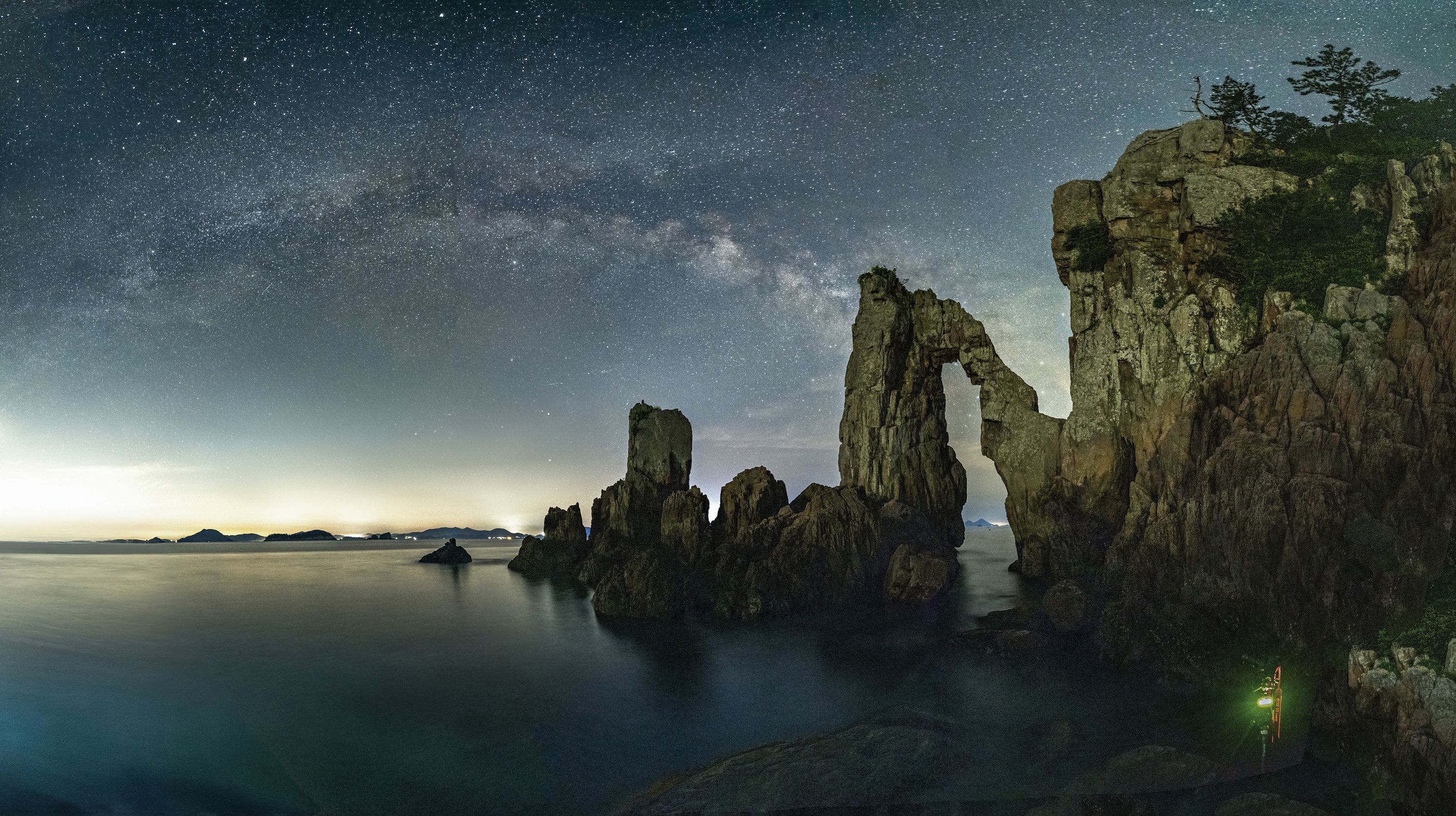 Long exposure and night view of Hwalgae Rock with cliff and hole on the sea against Milky Way in the sky at Guam-ri of Goheung-gun, South Korea