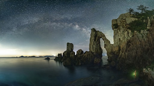 Long exposure and night view of Hwalgae Rock with cliff and hole on the sea against Milky Way in the sky at Guam-ri of Goheung-gun, South Korea