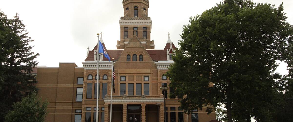A large brick building with a central dome and a flagpole with flags.