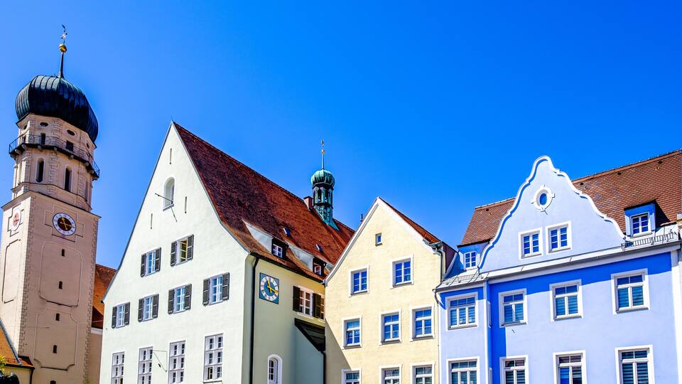 A row of colorful buildings with distinct architectural styles, including a clock tower and a church steeple.