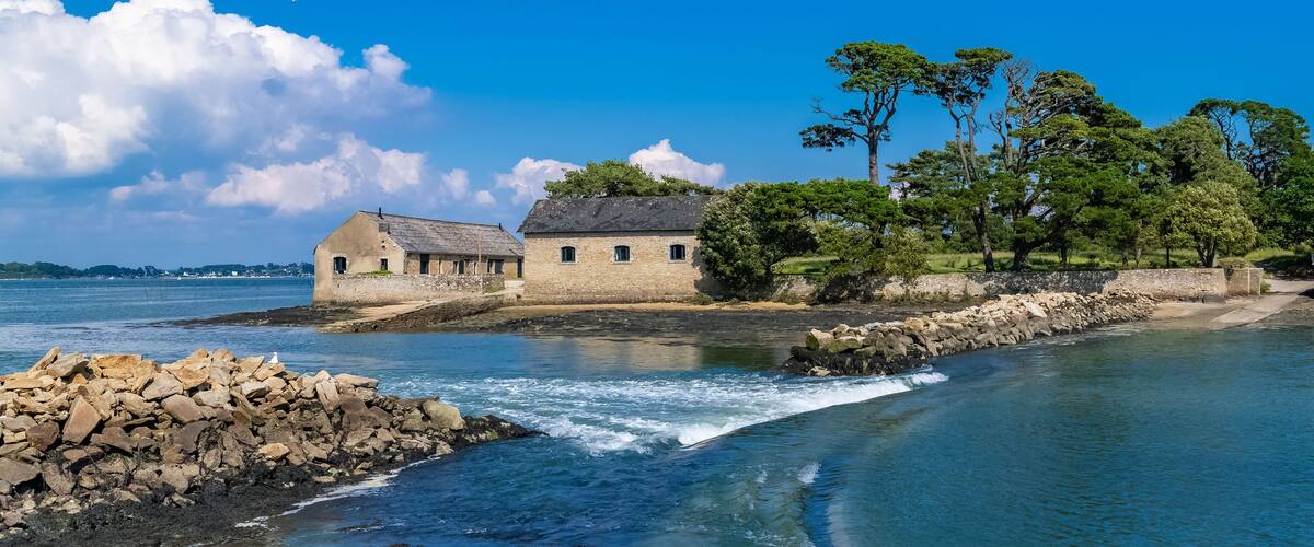 A coastal stone building with a stone wall and trees.