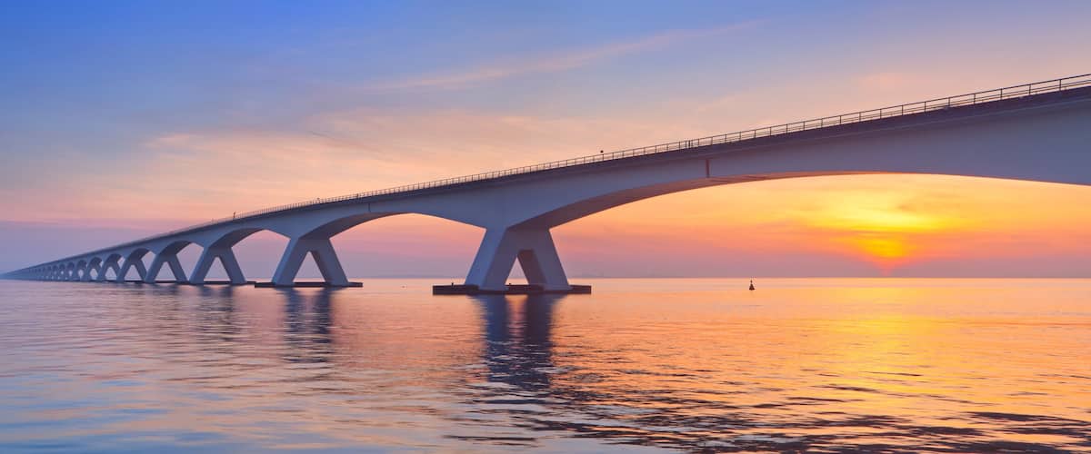 A bridge over calm water during sunset.