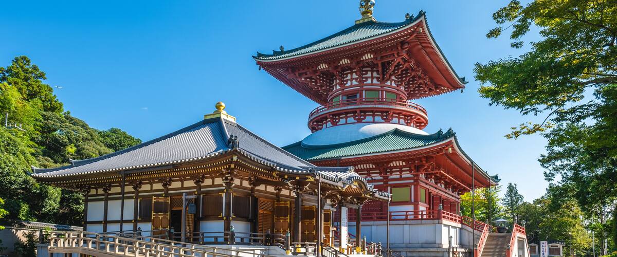 A traditional Japanese pagoda with a multi-tiered roof and a smaller adjacent building with a sloped roof.