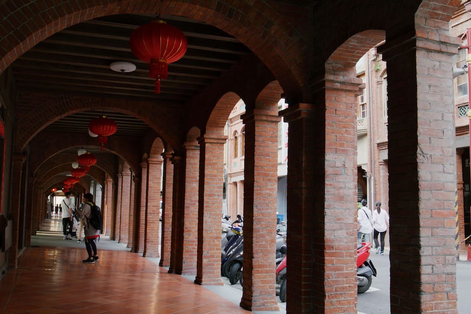Un porticato con archi in mattoni e lanterne rosse.