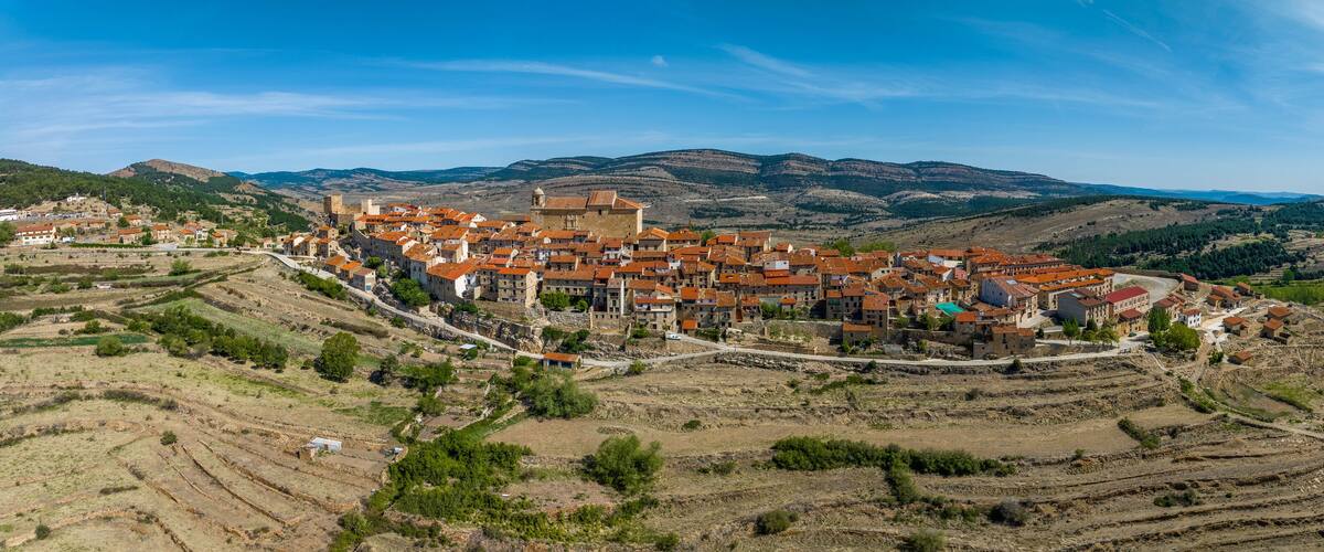 A village with terraced fields and a prominent castle-like structure.