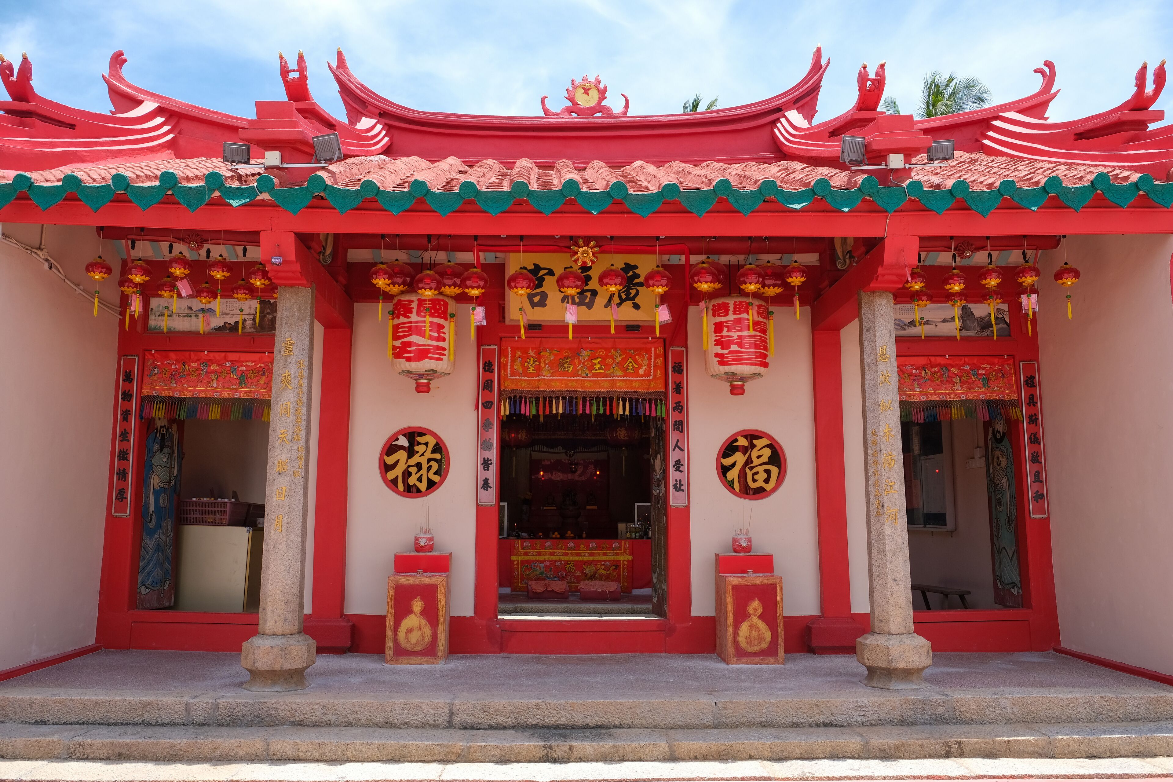 A traditional Chinese temple with red and green architecture, featuring ornate decorations and Chinese characters.