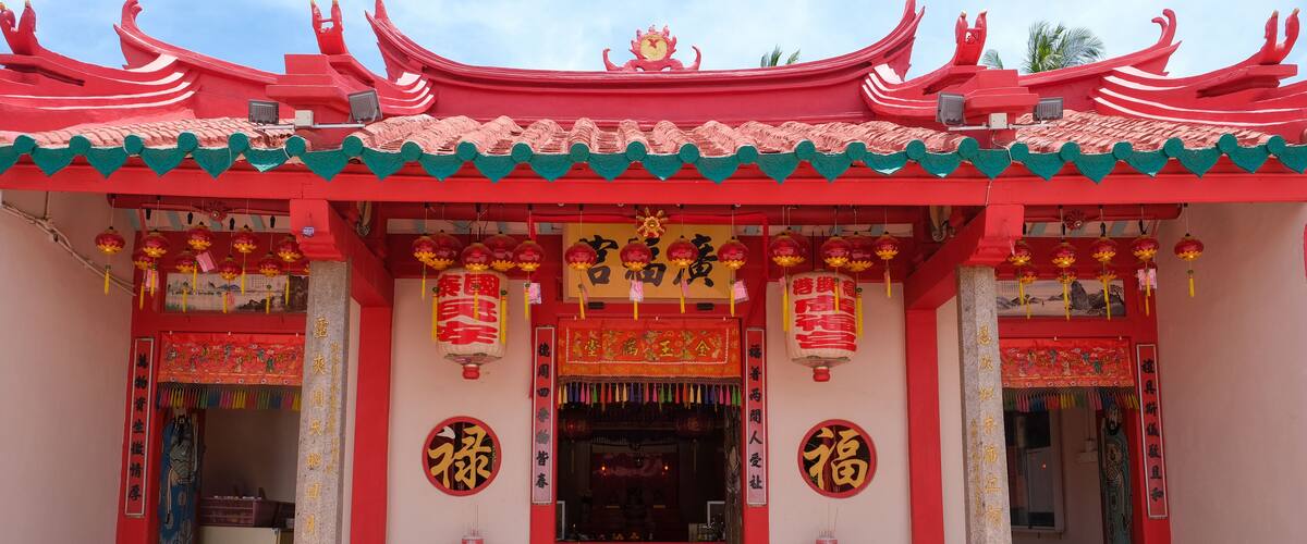 A traditional Chinese temple with red and green architecture, featuring ornate decorations and Chinese characters.