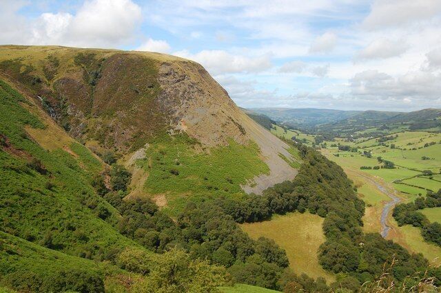 Une vallée traversée par une rivière, avec des collines douces et des champs qui s’étendent à perte de vue.
