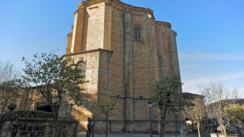Un bâtiment historique en pierre, doté d’un haut clocher et de fenêtres en arc de cercle.