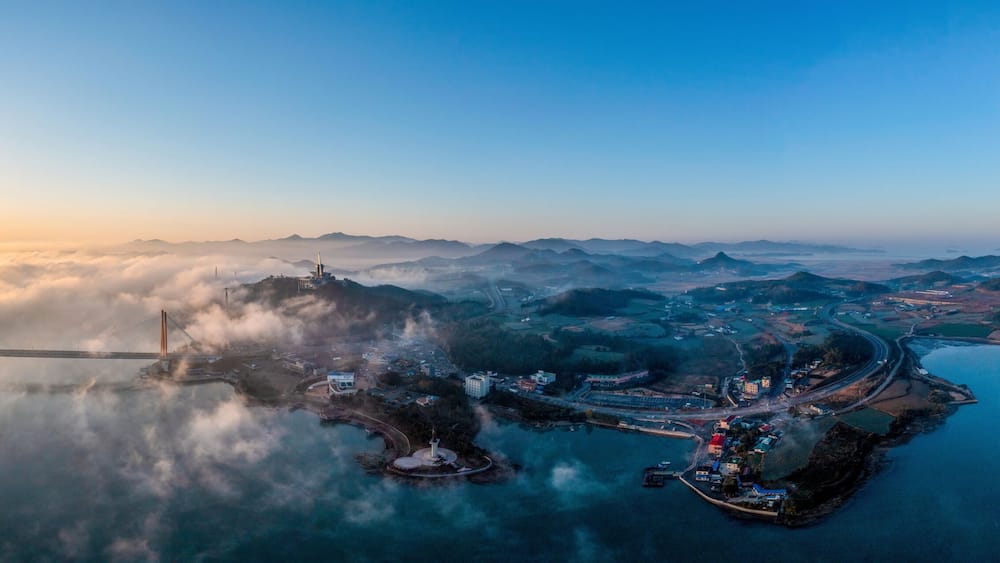 Aerial and panoramic view of sun rising over sea of clouds on Jindo Bridge and Uldolmok at Nokjin-ri near Jindo-gun, South Korea