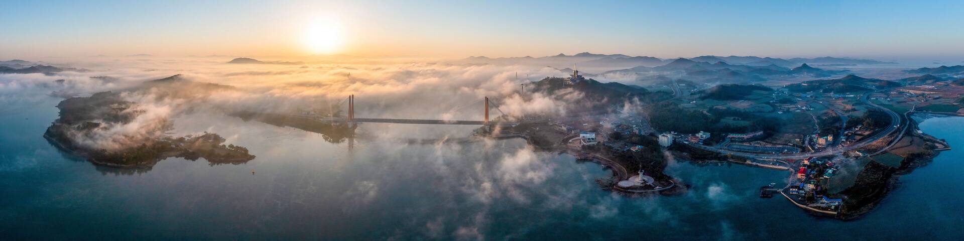 Aerial and panoramic view of sun rising over sea of clouds on Jindo Bridge and Uldolmok at Nokjin-ri near Jindo-gun, South Korea