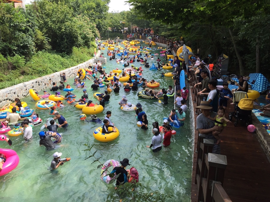 A crowded water park with people floating in colorful inflatable tubes.
