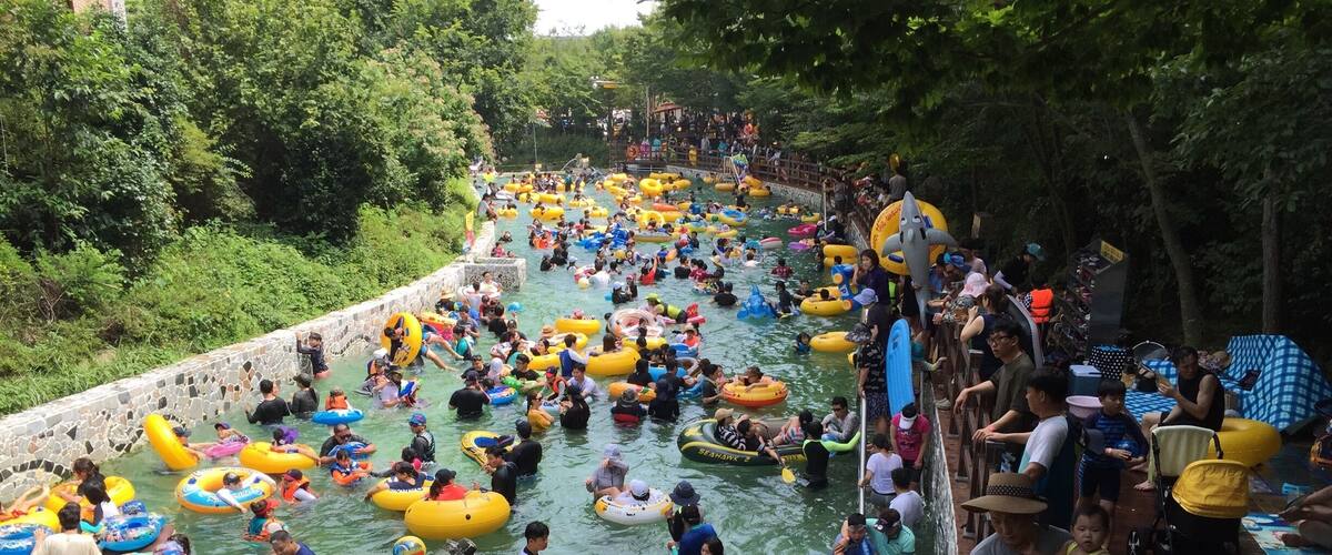A crowded water park with people floating in colorful inflatable tubes.