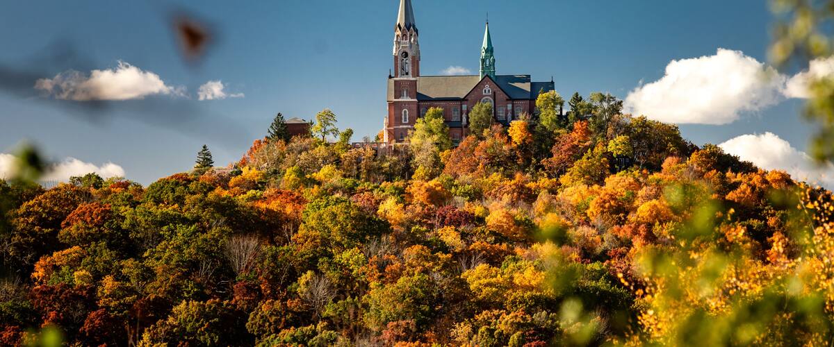 A church on a hill surrounded by autumn foliage.
