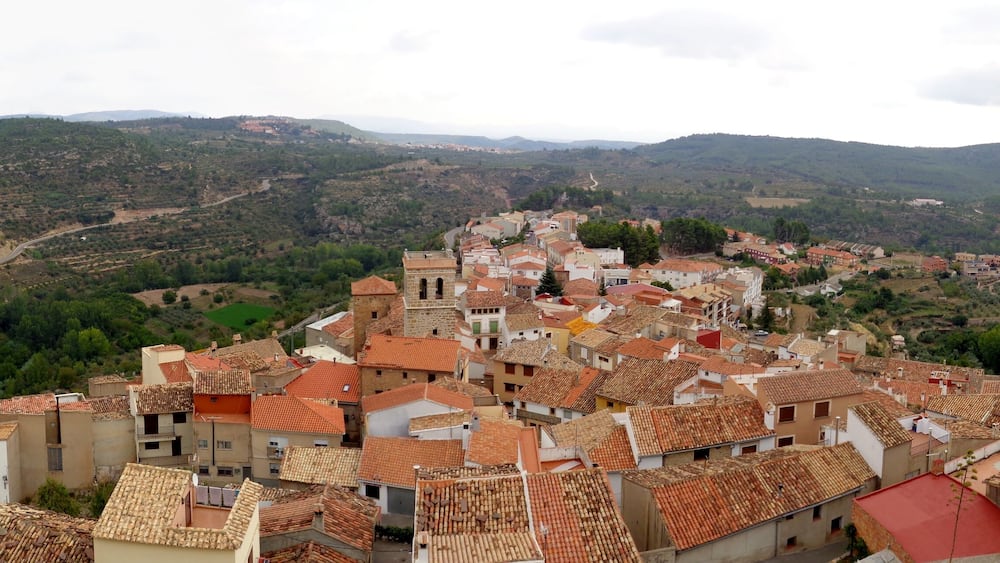 Une ville aux bâtiments aux toits de tuiles rouges, nichée dans une vallée entourée de collines.