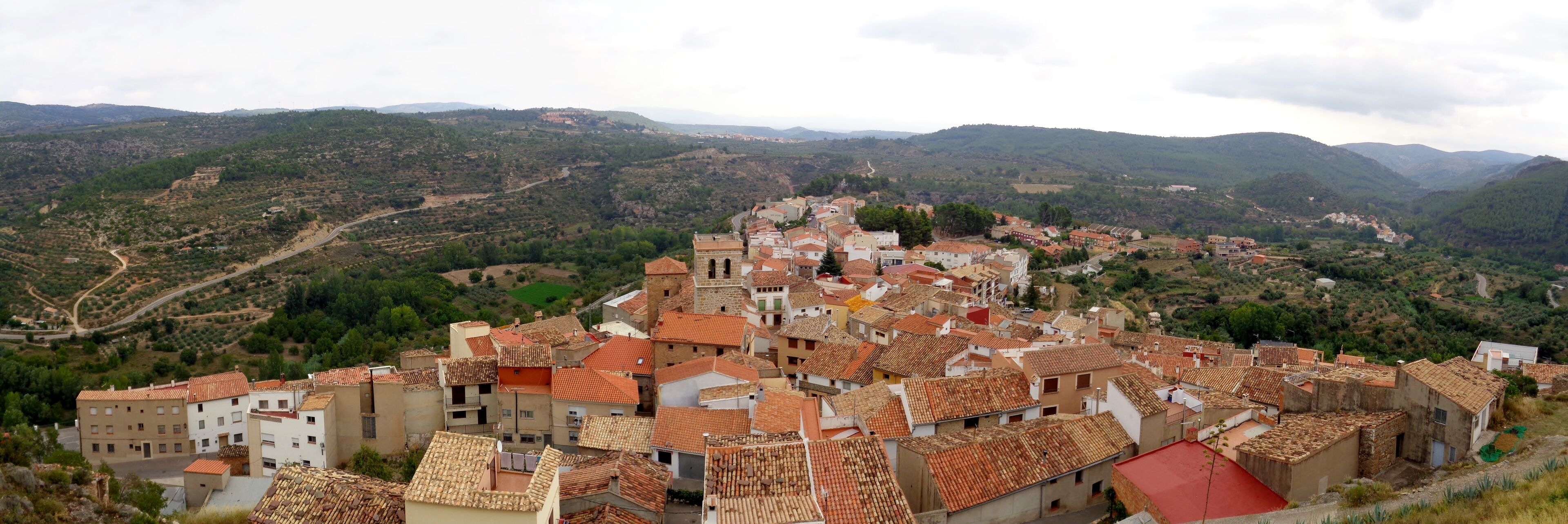 A town with terracotta-roofed buildings nestled in a valley surrounded by hills.