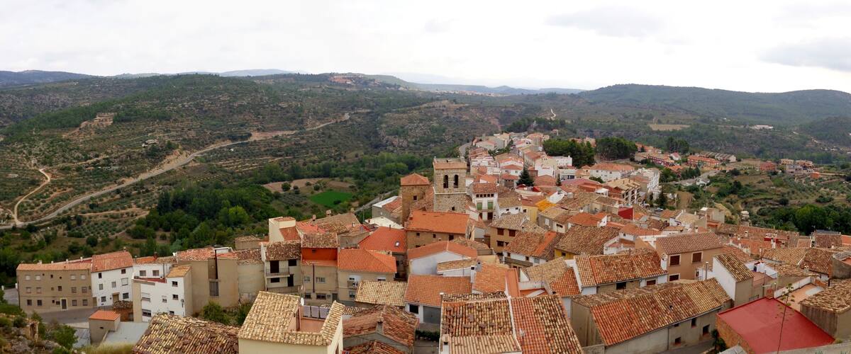 A town with terracotta-roofed buildings nestled in a valley surrounded by hills.