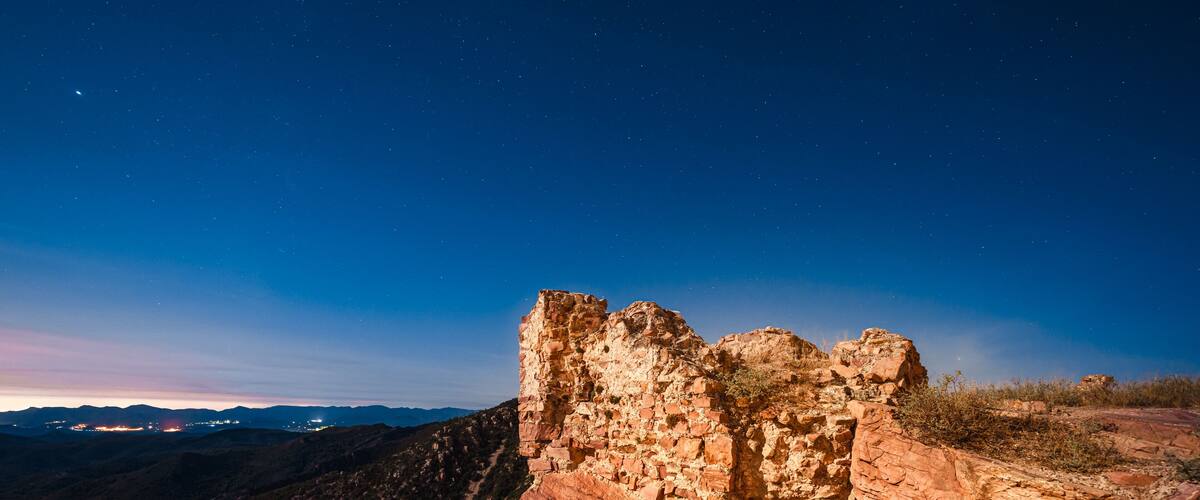 A rocky cliff with a starry night sky.