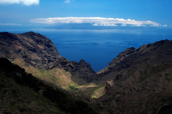 Un paysage montagneux avec une vallée profonde et une vue sur l’océan.