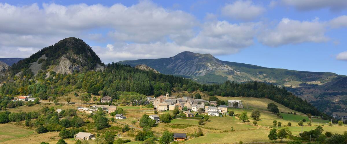 A village nestled in a valley with a prominent mountain in the background.