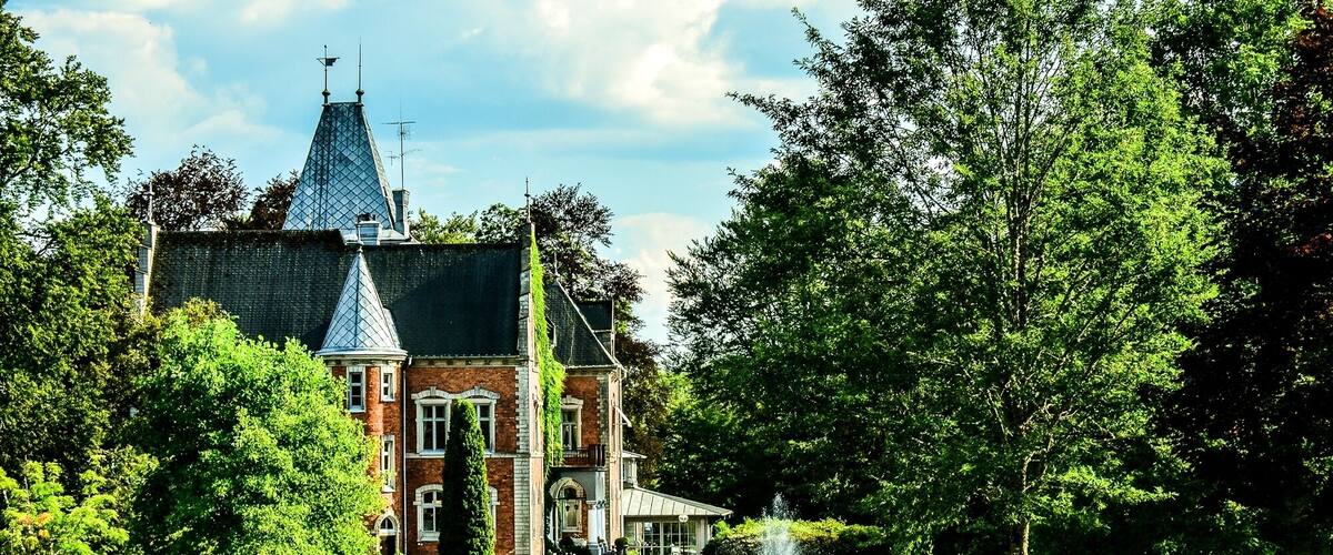 A large, historic building with a prominent tower and a well-maintained garden.