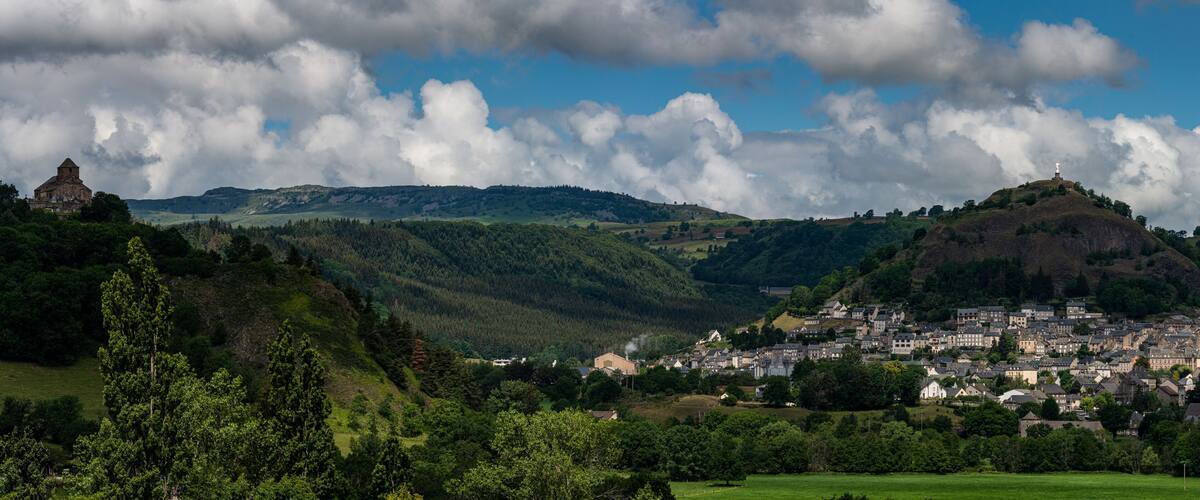 A town nestled in a valley with a prominent hilltop church and a statue on a hill.