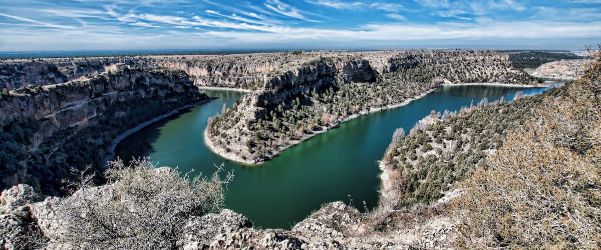 A canyon with a river, rocky terrain, and sparse vegetation.
