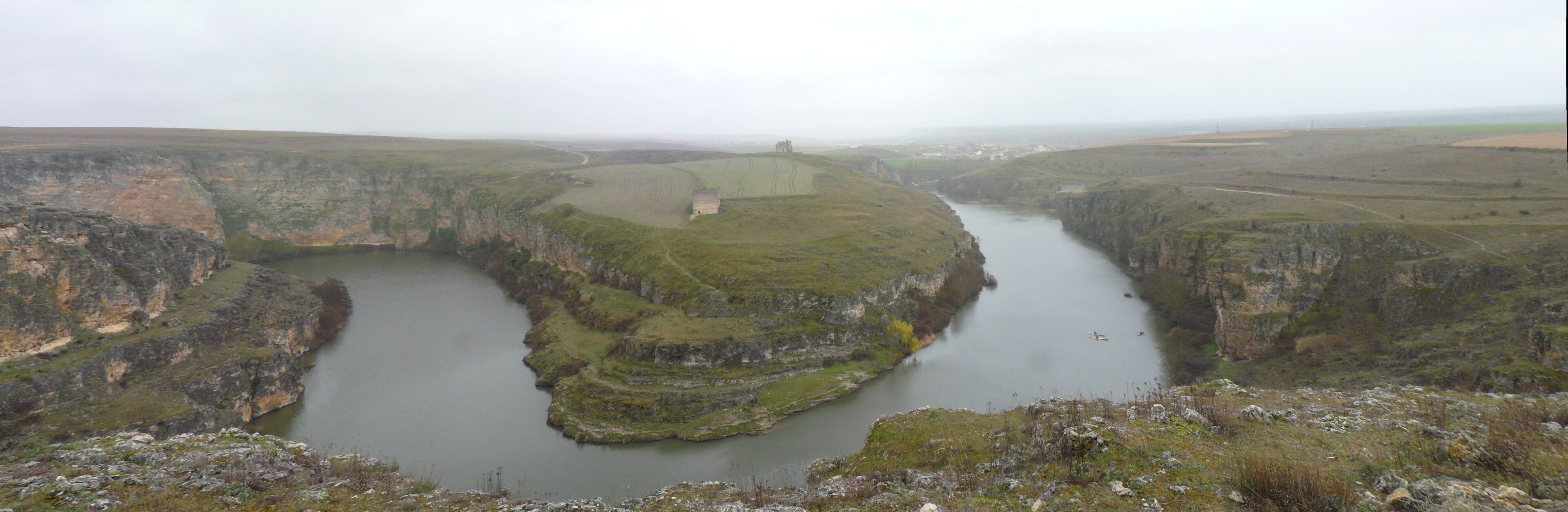 A river canyon with steep cliffs and a small boat on the water.