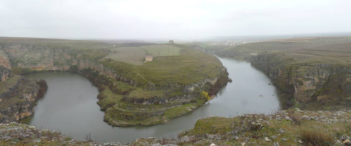 A river canyon with steep cliffs and a small boat on the water.