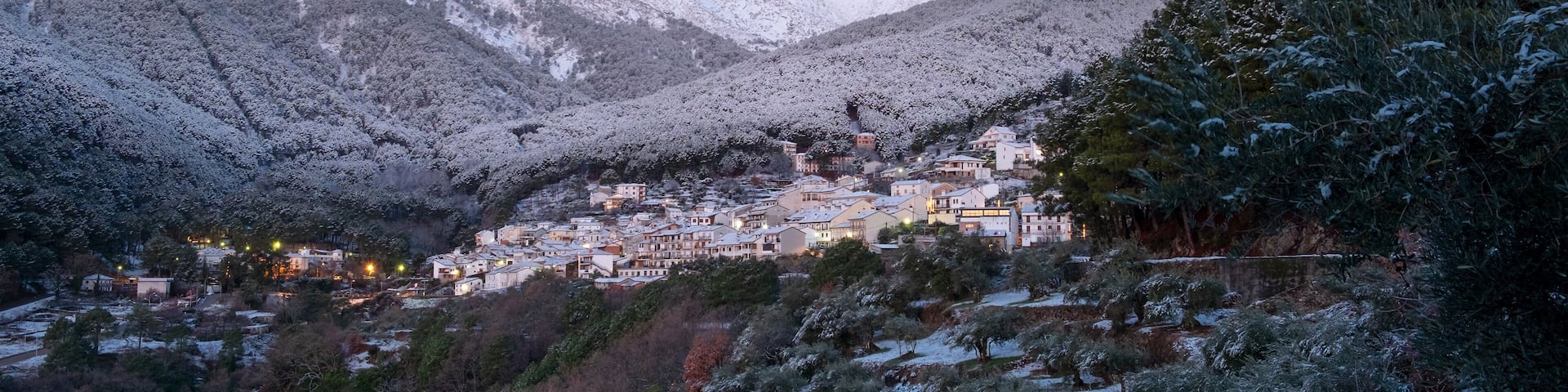 A snow-covered mountain village with houses nestled in the valley.