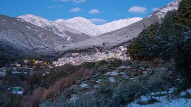Un pueblo en la montaña cubierto de nieve, con casas ubicadas en el valle.