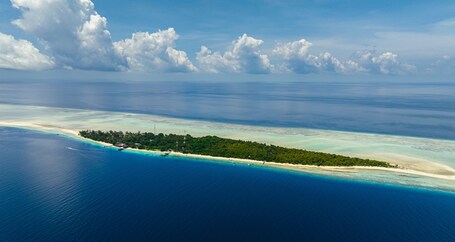 Eine Luftaufnahme einer tropischen Insel mit klarem türkisblauem Wasser, einem Sandstrand und üppiger Vegetation.