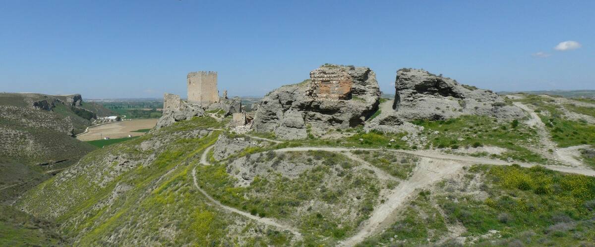 A castle on a hill with a surrounding landscape of rocky terrain and sparse vegetation.
