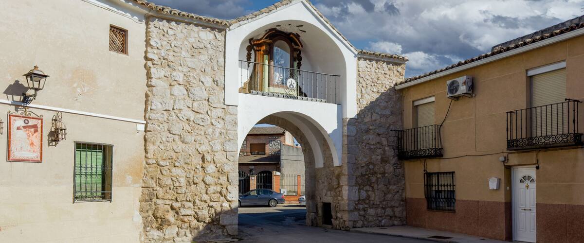 A street with stone buildings, an archway, and a car parked under the arch.