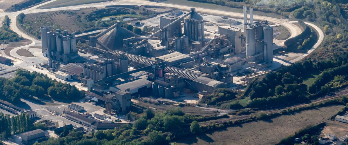 An industrial complex with multiple buildings, storage silos, and a curved road.