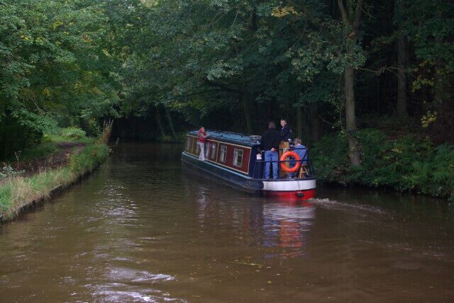 Llangollen Canal near Colemere. A boat heads into the avenue of trees approaching Little Mill Bridge.