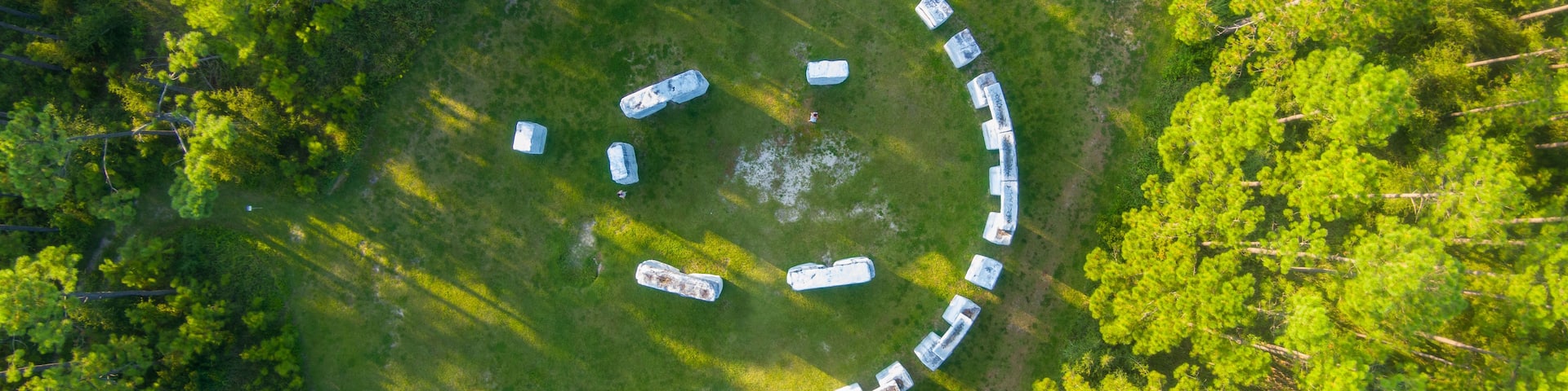 An aerial view of a circular arrangement of structures in a forested area.
