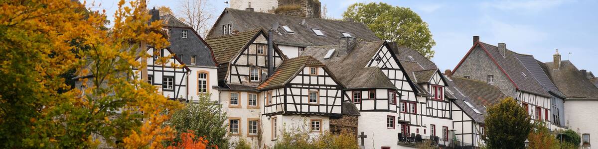 A historic town with timber-framed houses, a prominent tower, and autumn foliage.