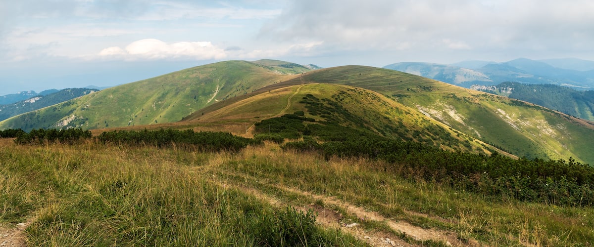 Rolling hills with a dirt path leading through a grassy area.