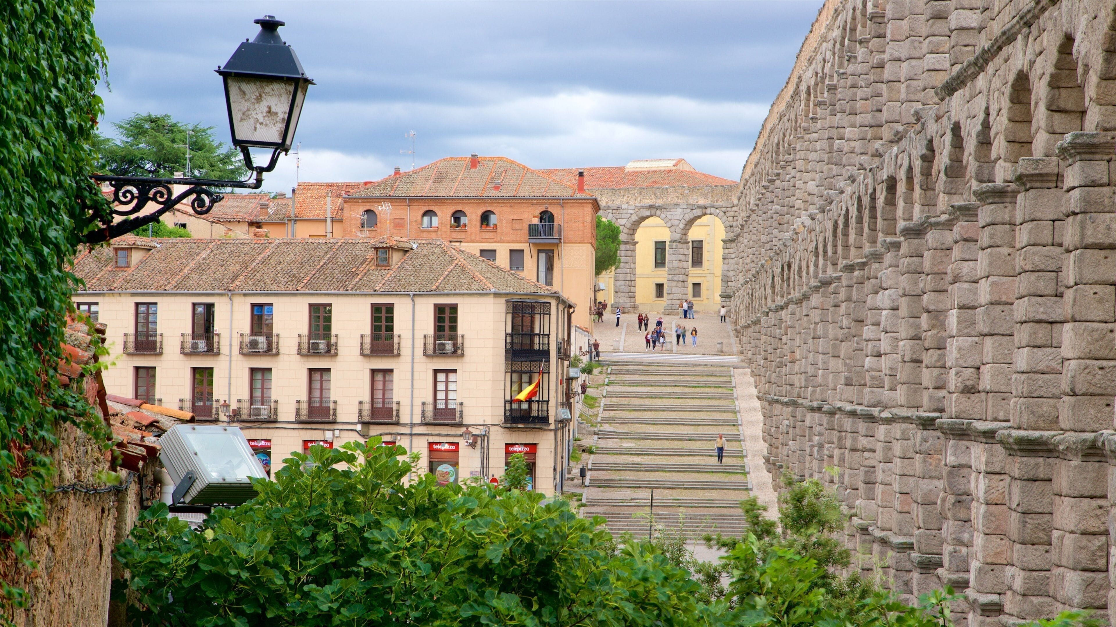 A street with buildings, a street lamp, and a staircase leading up to a yellow building.