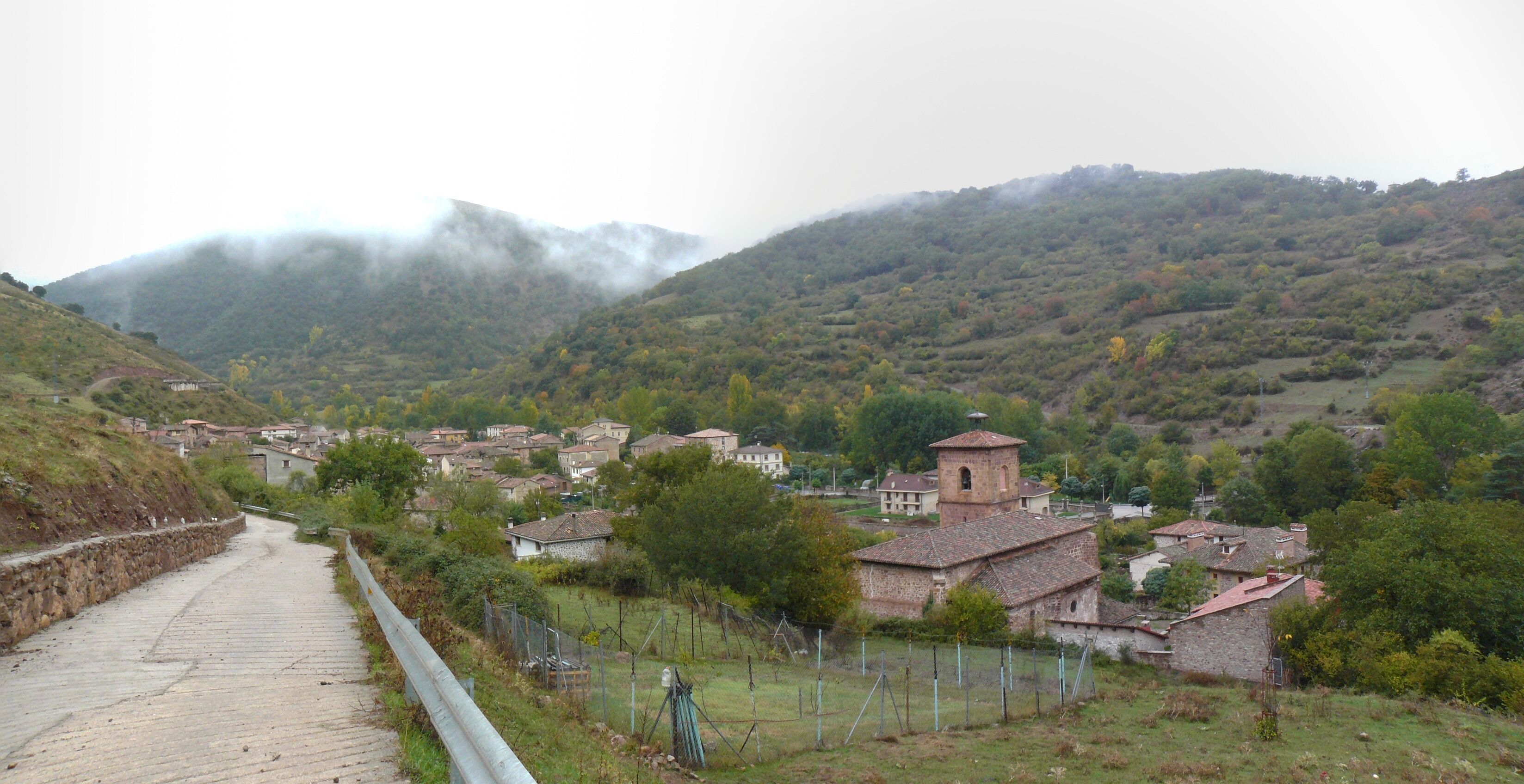 A village with stone houses, a church, and a mountain in the background.