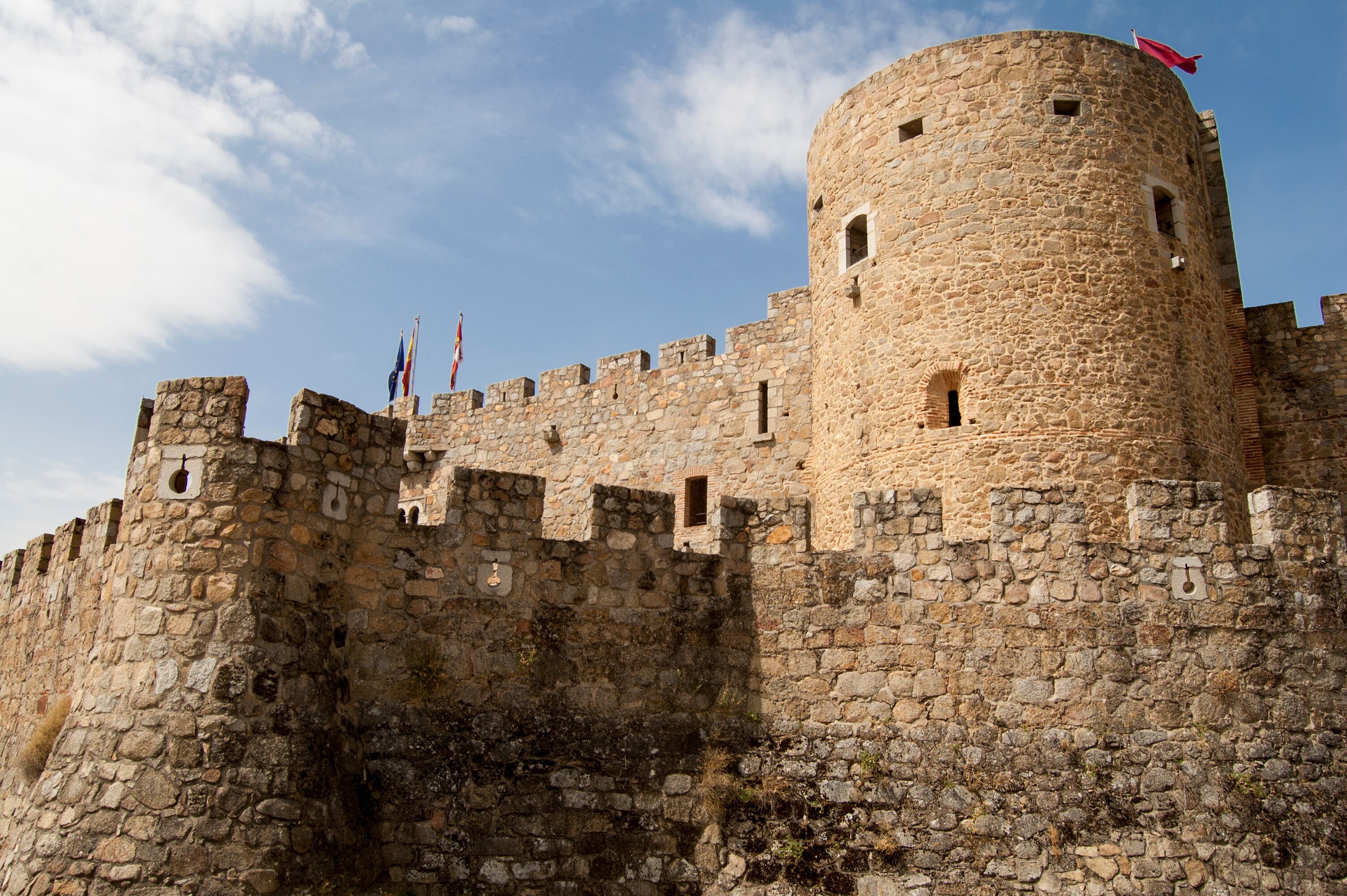 A historic stone castle with multiple towers and flags.